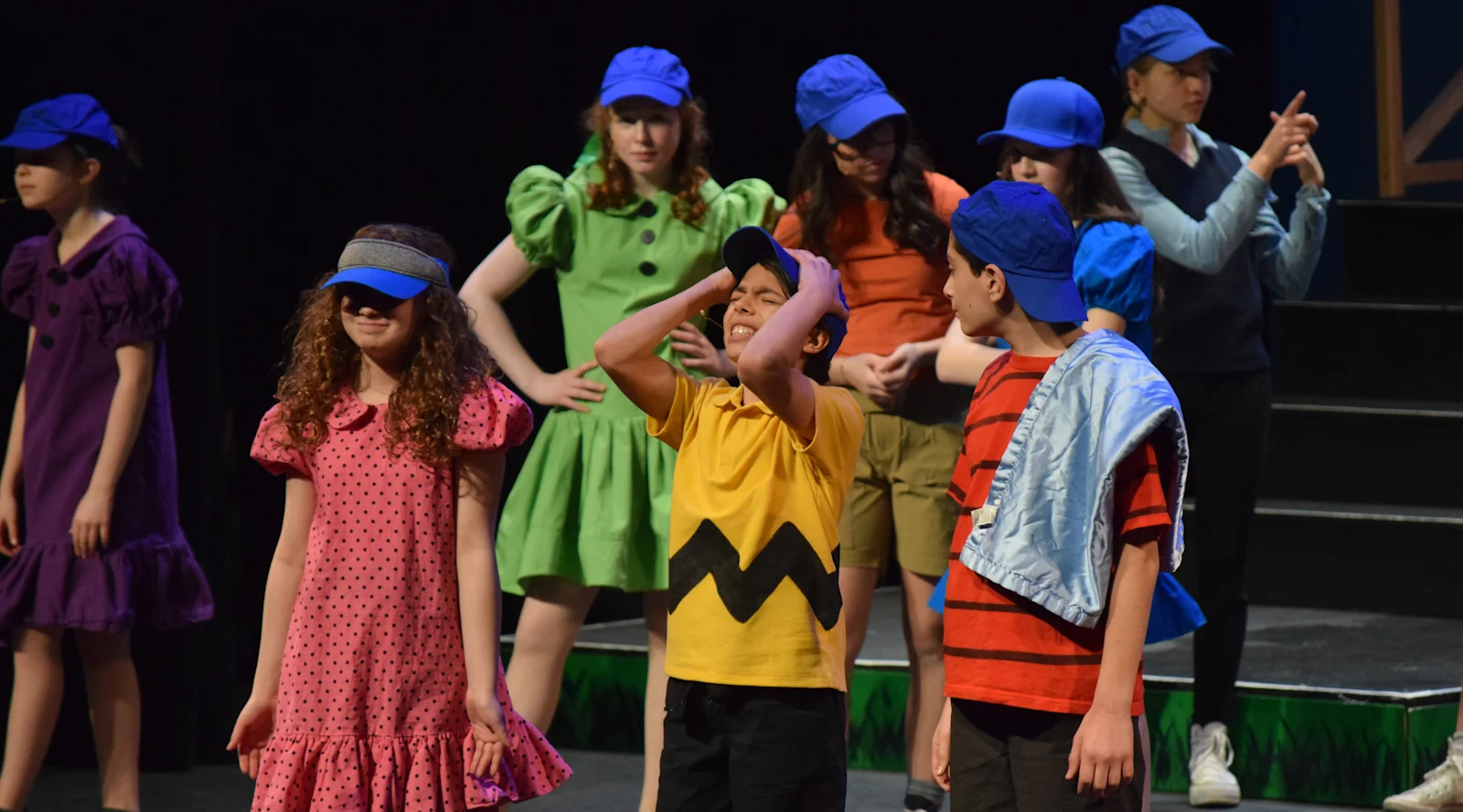 students in colorful costumes perform in %22You're a Good Man, Charlie Brown%22